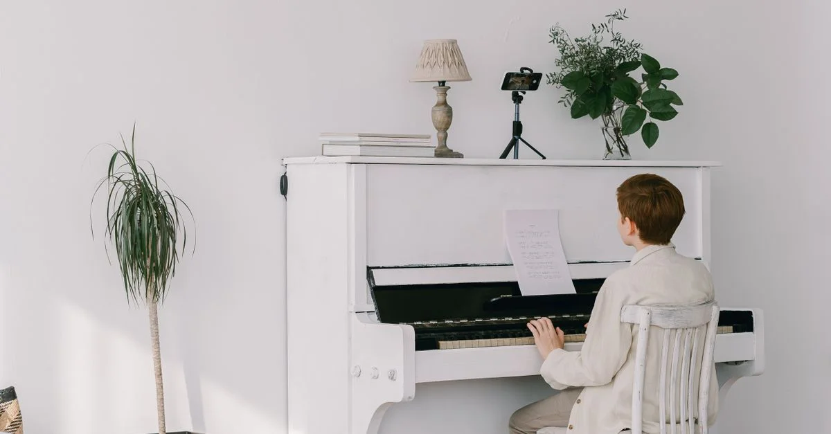 Un jeune musicien joue du piano dans une pièce lumineuse et minimaliste, mettant en valeur une créativité paisible.