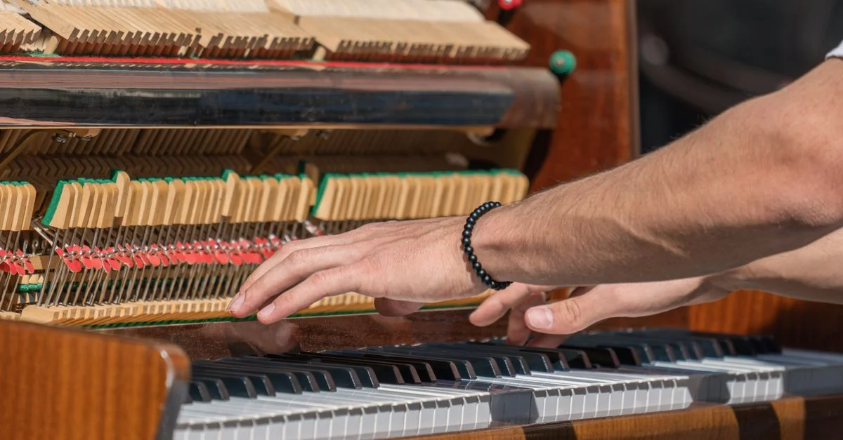 Un aperçu détaillé des mains jouant d'un piano droit avec des composants internes visibles.