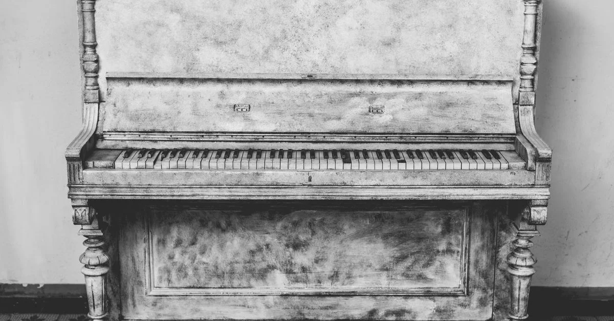 Un magnifique piano droit antique, magnifiquement vieilli, en photographie en noir et blanc. Parfait pour des thèmes de décoration vintage.