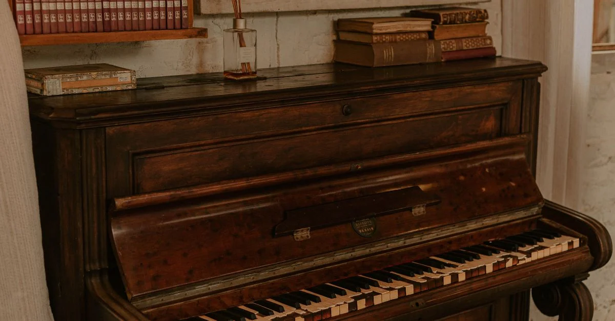 Ancien piano dans une pièce confortable avec des livres et décor anciens, créant une atmosphère vintage.