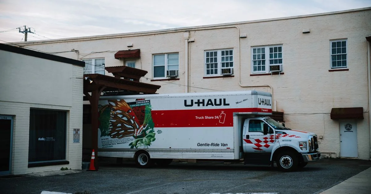 Un camion U-Haul garé devant un bâtiment d'entrepôt beige.