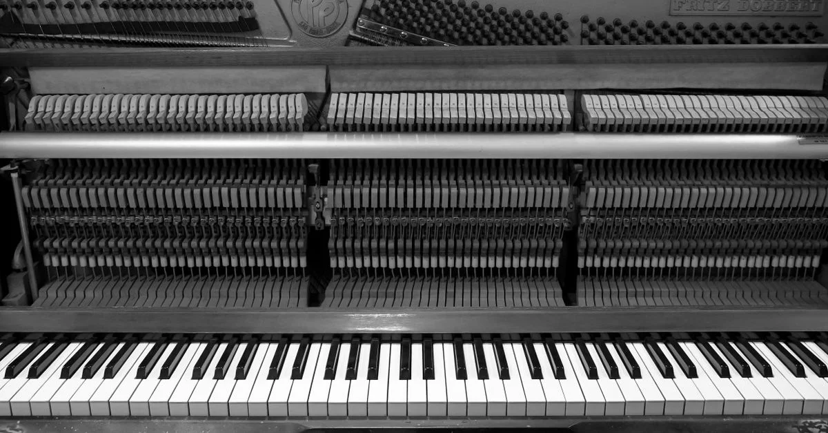 Une vue détaillée en noir et blanc d'un piano droit montrant des touches et des marteaux pour un look musical classique.