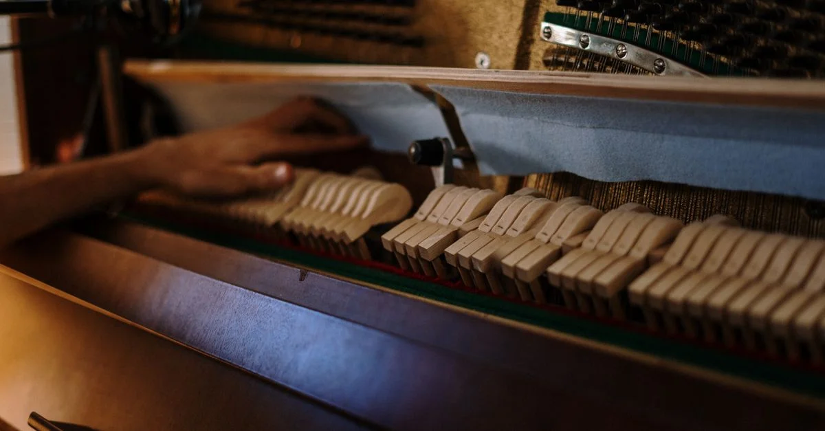 Vue détaillée de l'intérieur d'un piano lors d'une session d'accord, mettant en valeur les cordes et les marteaux.