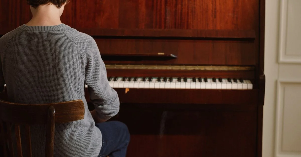Une personne assise et pratiquant le piano à l'intérieur, créant une atmosphère musicale sereine.