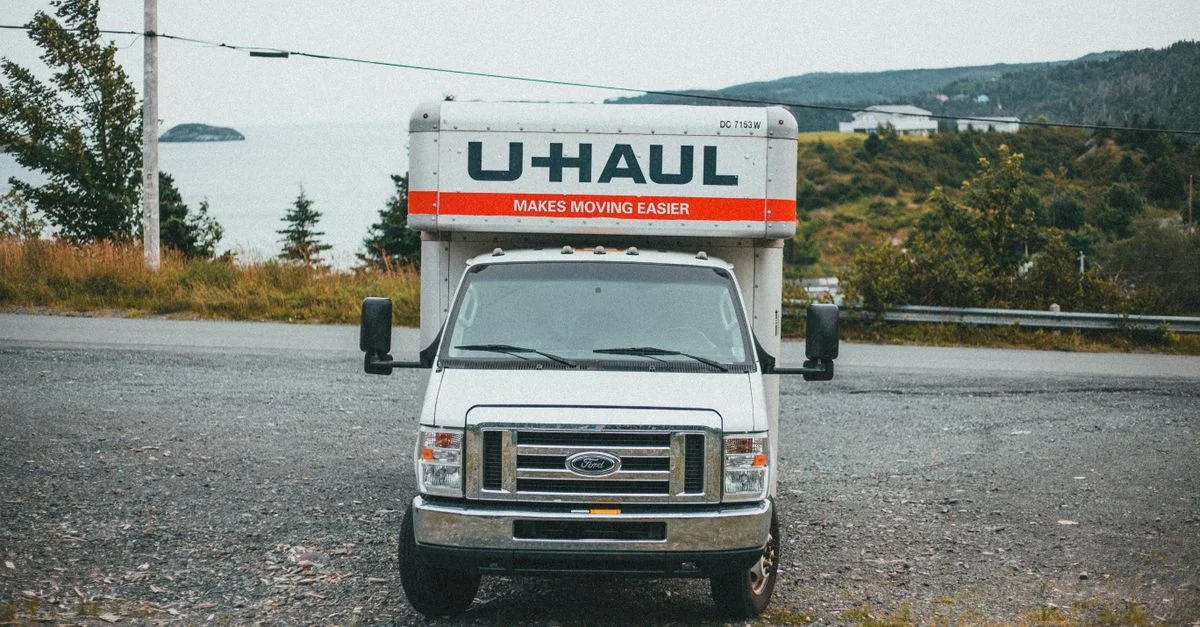 Un camion U-Haul garé sur une route en terre avec un paysage extérieur pittoresque, idéal pour les promotions de services de déménagement.